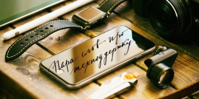 На деревянной поверхности часы, металлическая табличка с надписью